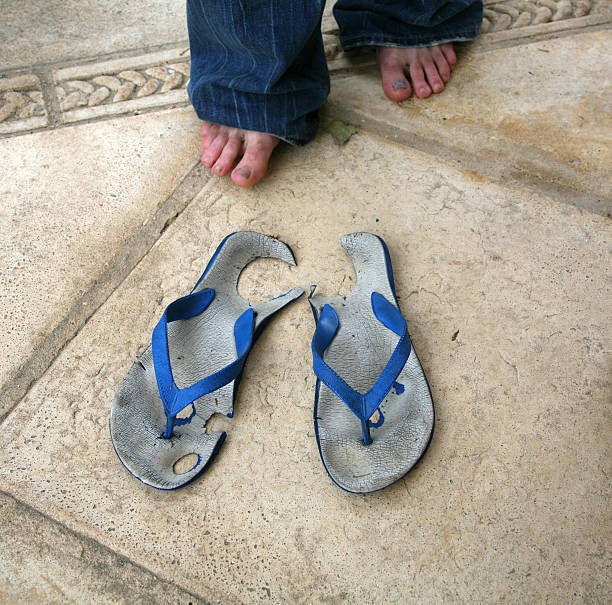 Man's Feet with Worn Through and Old Flip-flop Sandals stock photo