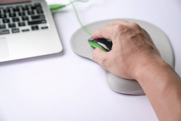 Man's hand clicking on mouse, resting his wrist on wrist rest or support memory foam. stock photo