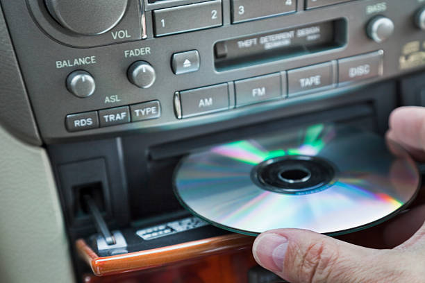 man's hand inserting CD in car player stock photo