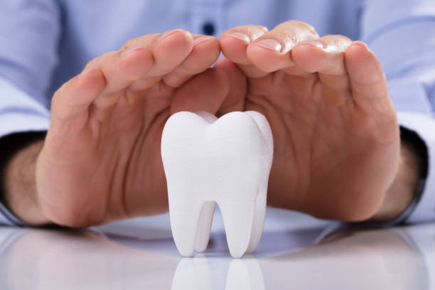 Man's Hand Protecting White Tooth Man's Hand Protecting Healthy Hygienic White Tooth On Reflective Table enamel stock pictures, royalty-free photos & images