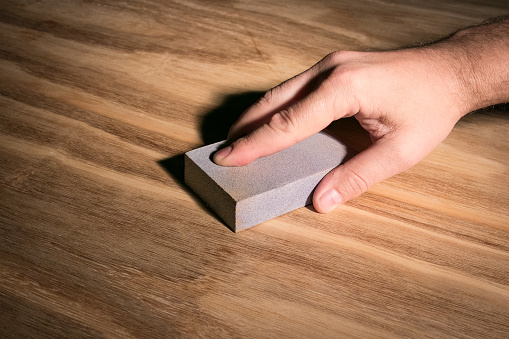 Mans Hand Sanding Wood Grain Using Sandpaper Sponge Block To