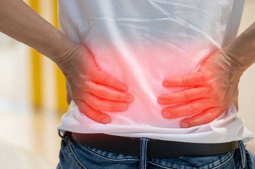 Man's hands on his back with red spot as suffering on backache. Male person sick from lower back pain from Herniated or slipped discs,Degenerative, sacroiliac joint, spinal stenosis, Pancreatic Cancer