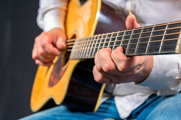 Man's hands playing acoustic guitar stock photo