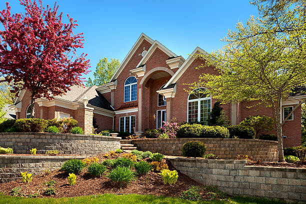 mansion home exterior design; terraced paved landscape, colorful spring foliage - bakstenen huis stockfoto's en -beelden