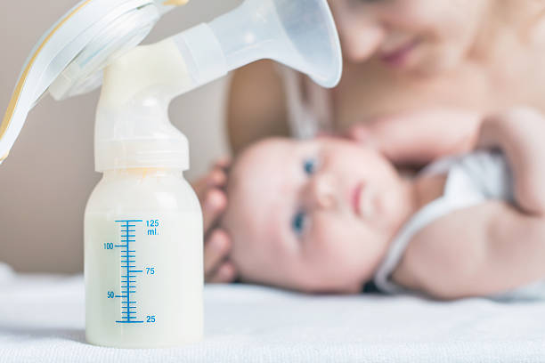 Manual breast pump and milk at background stock photo