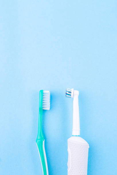Manual toothbrush versus electric toothbrush, blue background, copy space, vertical stock photo