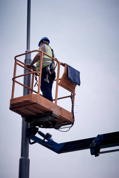 Manual worker on a telescopic lifter basket fixing street light pole. stock photo
