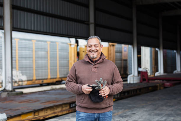Manual worker standing outdoors at shipping port A mature Hispanic man in his 40s with a beard, a manual worker at a shipping port, standing outdoors in a storage area. blue collar worker stock pictures, royalty-free photos & images
