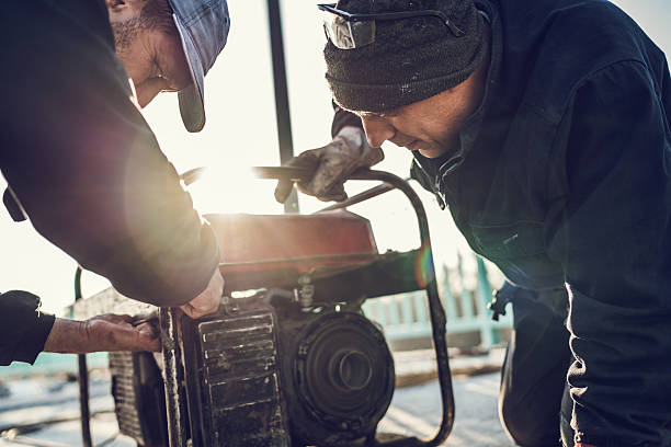 Manual workers repairing power generator. Two construction workers repairing power generator outdoors. portability stock pictures, royalty-free photos & images