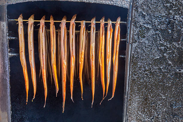 many hanging eels are being smoked - paling stockfoto's en -beelden