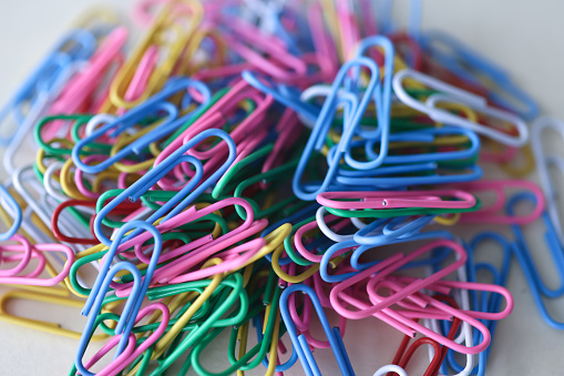 Many multicolored paper clips lying on table closeup. Sale of stationery concept