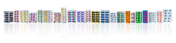 Many of colorful pills in blister packs in a row isolated on white background with copy space. Pharmaceuticals industry. Healthcare education in hospital. Pharmacology. Painkiller and antibiotics Many of colorful pills in blister packs in a row isolated on white background with copy space. Pharmaceuticals industry. Healthcare education in hospital. Pharmacology. Painkiller and antibiotics pics for amoxicillin stock pictures, royalty-free photos & images