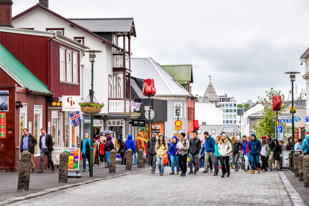 Many people tourists walking on street sidewalk in downtown center by stores shops restaurant with signs in summer Reykjavik, Iceland - June 19, 2018: Many people tourists walking on street sidewalk in downtown center by stores shops restaurant with signs in summer reykjavik stock pictures, royalty-free photos & images