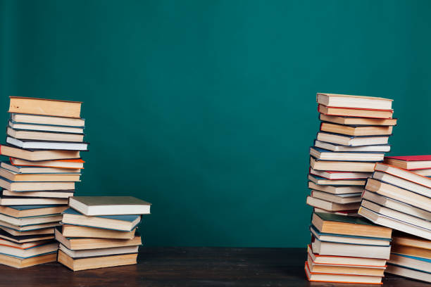 vele stapels onderwijsboeken in de universitaire bibliotheek op een groene achtergrond - book tower stockfoto's en -beelden