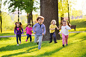 istock many young children smiling running along the grass in the park 1303931593