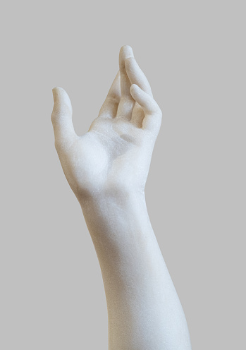 side view closeup of white stone marble statue hand reaching out to the heavens isolated on grey background