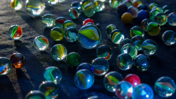 Marbles scattered with rays of light hitting the background. stock photo
