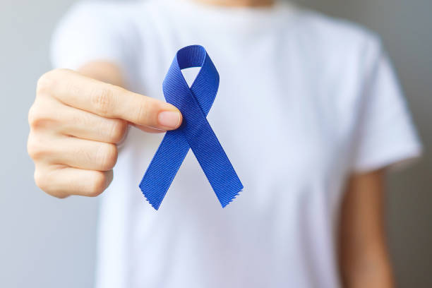 March Colorectal Cancer Awareness month, Woman holding dark Blue Ribbon for supporting people living and illness. Healthcare, hope and World cancer day concept stock photo