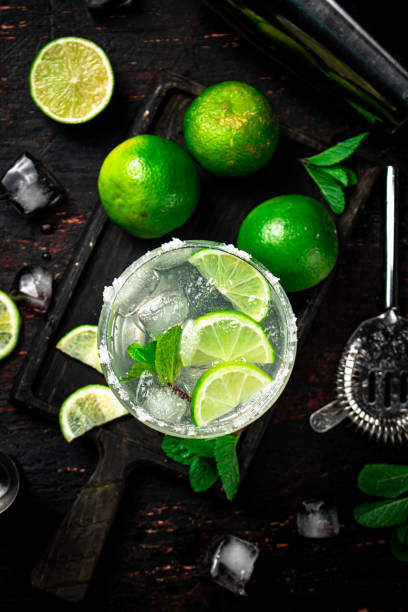 Margarita on a cutting board with pieces of lime and mint leaves. stock photo