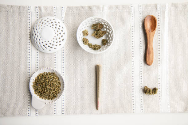 Marijuana Product Neatly Laid Out on Surface. Buds, Joint, Flower, Ground Cannabis, Wooden Spoon, Bowl - Top Down - Minimalist Cannabis stock photo