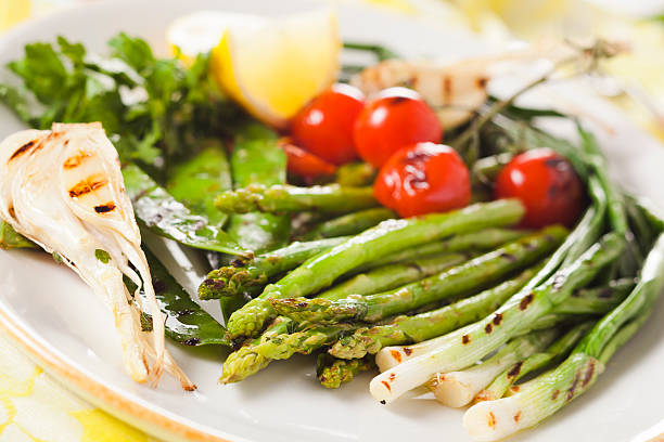 marinated grilled vegetables - asparagus, onions, peas, tomatoes stock photo