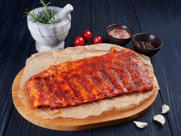 Marinated raw pork spare ribs on crumpled paper on a bamboo cutting board stock photo