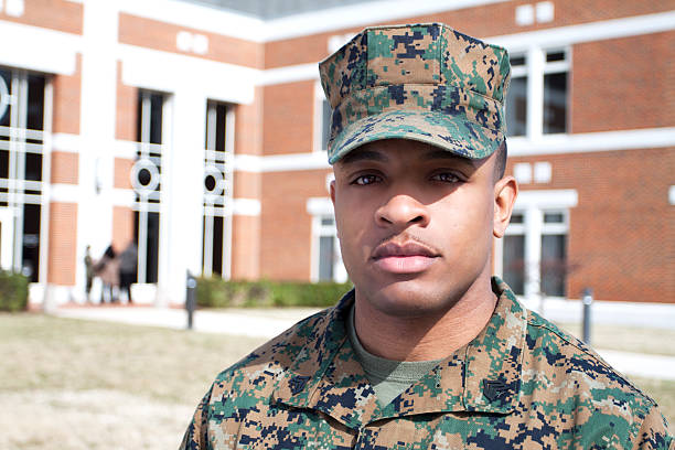Marine in Front of a Building Marine standing in front of a building while a group of people stand and talk in the background. military schools stock pictures, royalty-free photos & images