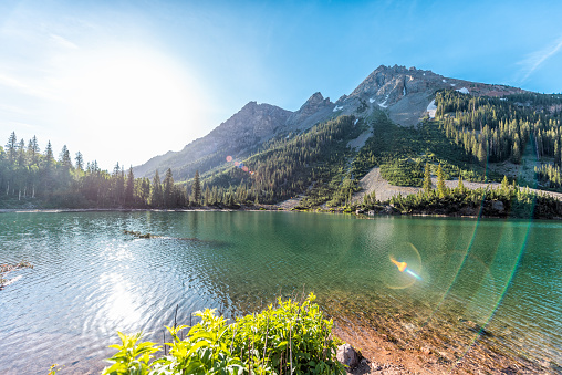 Maroon Bells rocky mountain snow peak view with Creater Lake in Colorado in summer wide angle view with bright sun and flare