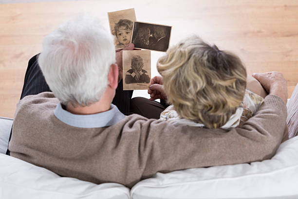 Marriage looking at photos Senior marriage sitting on the sofa and looking at old photos 2015 photos stock pictures, royalty-free photos & images