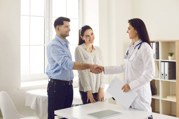 Married couple shakes hands with a female gynecologist while getting acquainted. stock photo