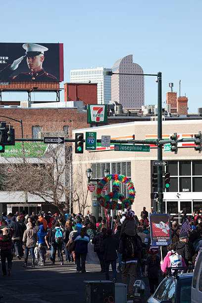 Martin Luther King Jr. march towards Denver "Denver, Colorado, U.S.A. - January 21, 2013: During a Martin Luther King Jr. Day parade, a diverse crowd of people, some holding signs in the air including a flowery peace symbol, march down Colfax Ave. past various buildings, a 7-Eleven sign and a Marine billboard with the Denver skyline in the distance." martin luther king jr day stock pictures, royalty-free photos & images