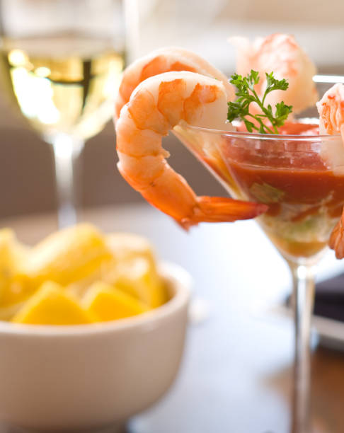 A martini glass of shrimp cocktail and a bowl of lemons stock photo