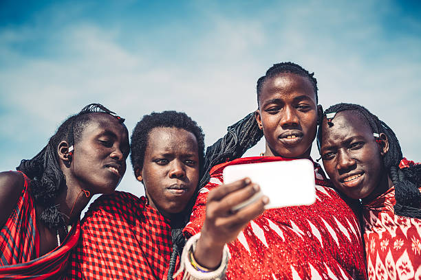 Masai Taking A Selfie Group of Masai warriors in traditional clothing taking a selfie with smart phone (Zanzibar, Africa). maasai warrior stock pictures, royalty-free photos & images