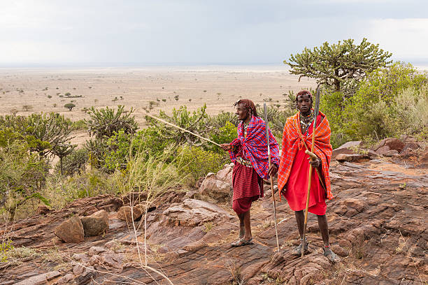 Masai warriors preparing for a hunt Two Masai warriors standing and looking away masai warrior stock pictures, royalty-free photos & images