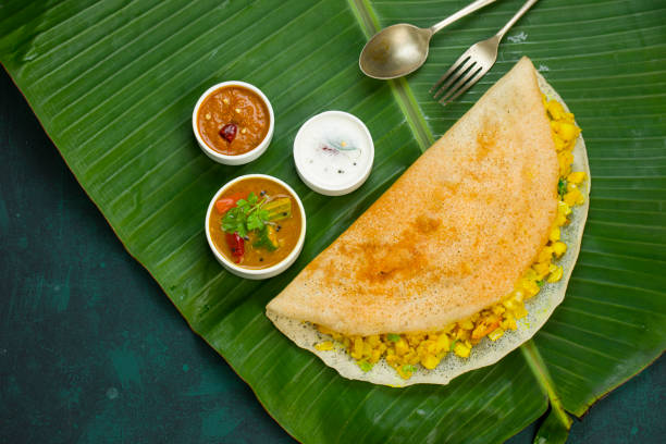 Masala sin Dosa _Masala dosa,famous south Indian breakfast item which is made in caste iron pan in traditional way and arranged on a fresh banana leaf,with dark green  background ,isolated. thosai stock pictures, royalty-free photos & images