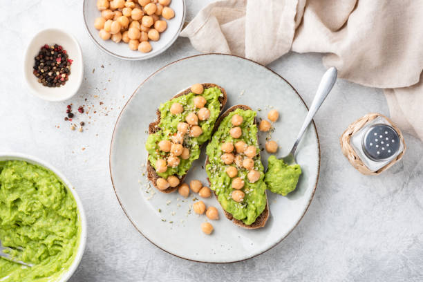 Mashed avocado and chickpeas on toasted bread stock photo