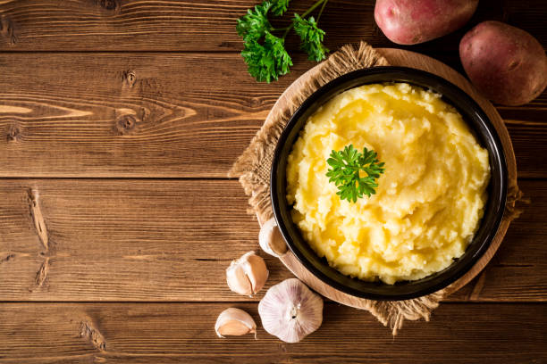 Mashed potatoes with butter and fresh parsley in bowl on rustic wooden table stock photo