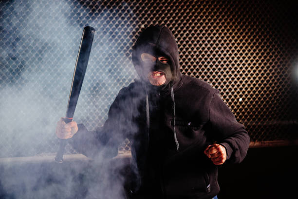 Masked angry man with bat in smoke stock photo