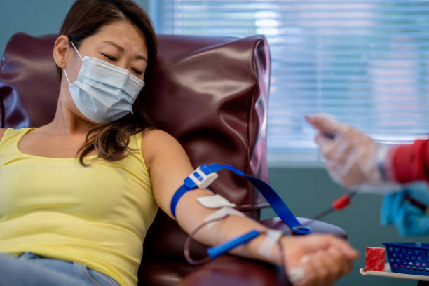 Masked Asian woman at a blood donation drive stock photo