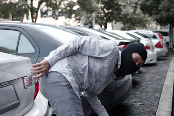 Masked thief in black balaclava trying to break into car. Criminal crime concept. Masked thief in black balaclava trying to break into car. Criminal crime concept. ski mask criminal stock pictures, royalty-free photos & images