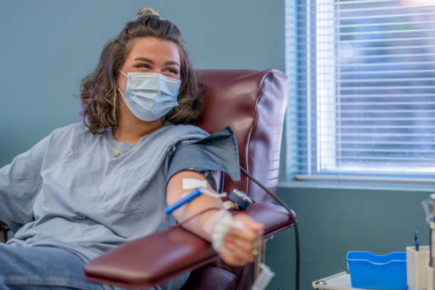 Masked young woman happy to be donating blood stock photo