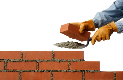 A brick layer building a brick wall.