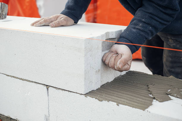 Masonry. Worker laying autoclaved aerated concrete blocks. Builder installing white blocks close up. Process of house building at construction site stock photo