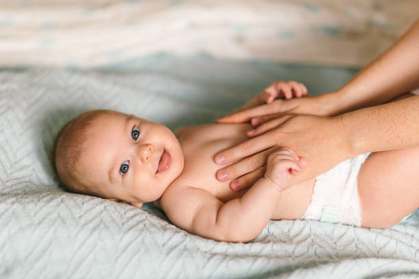 massage för barnet. fyra månader gamla bebis leende gör gymnastik - baby bildbanksfoton och bilder