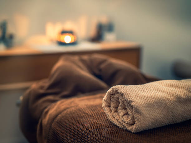 Massage table with towels and candle in a cabinet stock photo