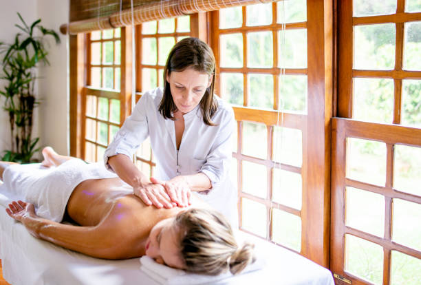 massage-therapeut in massage in einer schönen frau - masseur stock-fotos und bilder