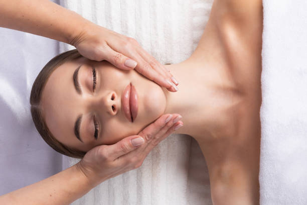 Massage therapist massaging woman face stock photo