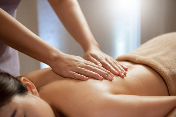 Masseuse doing massage on Asian female body in the spa salon. stock photo