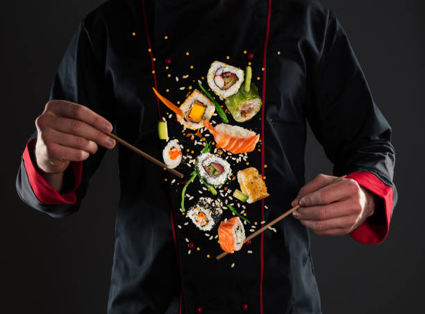 meisterchef hält stäbchen mit fliegendem sushi - asiatischer koch stock-fotos und bilder