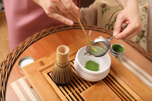 Master preparing matcha drink at wooden table, closeup. Tea ceremony